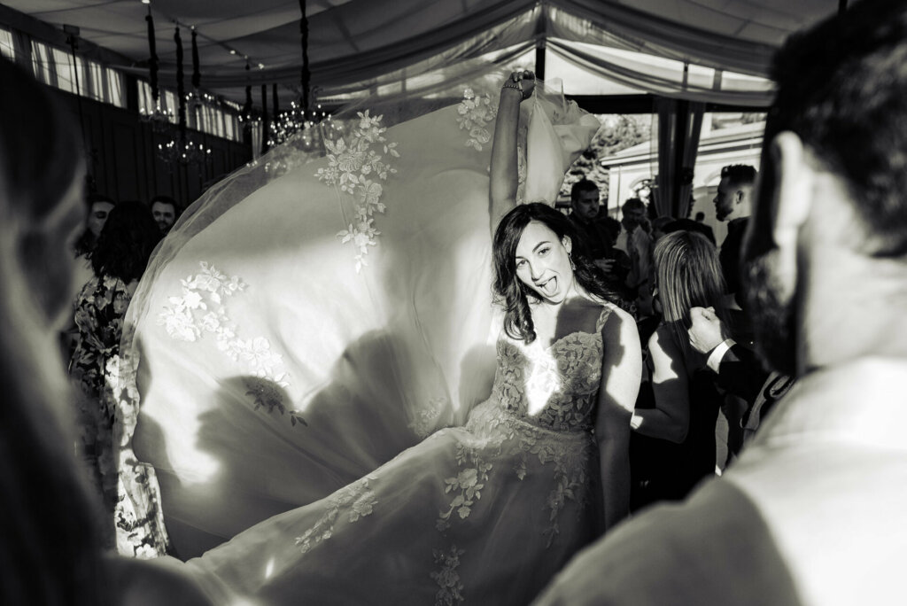 Elegant black and white image of the bride gracefully holding up her gown during the wedding reception.