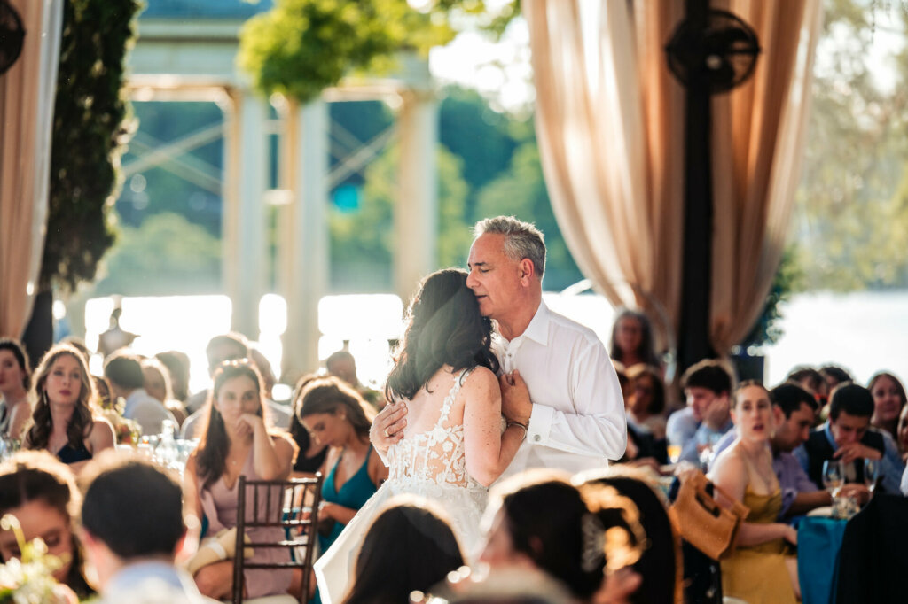 Tender moment captured as the bride's father embraces her during their dance at the wedding reception.