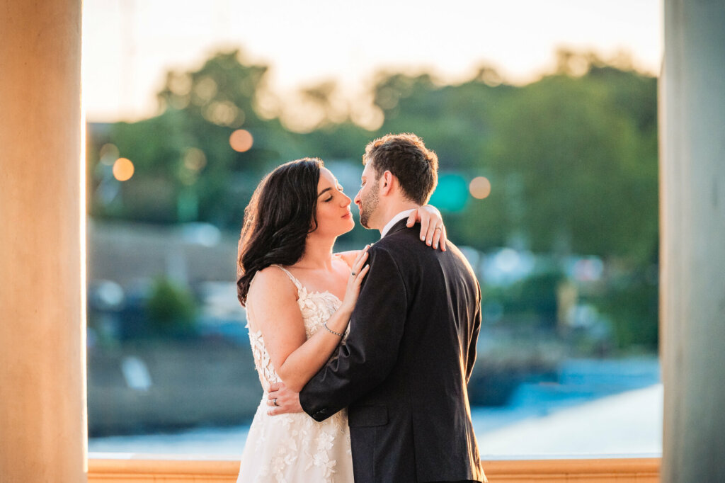 Newlyweds share a romantic kiss on a picturesque lakeside terrace.