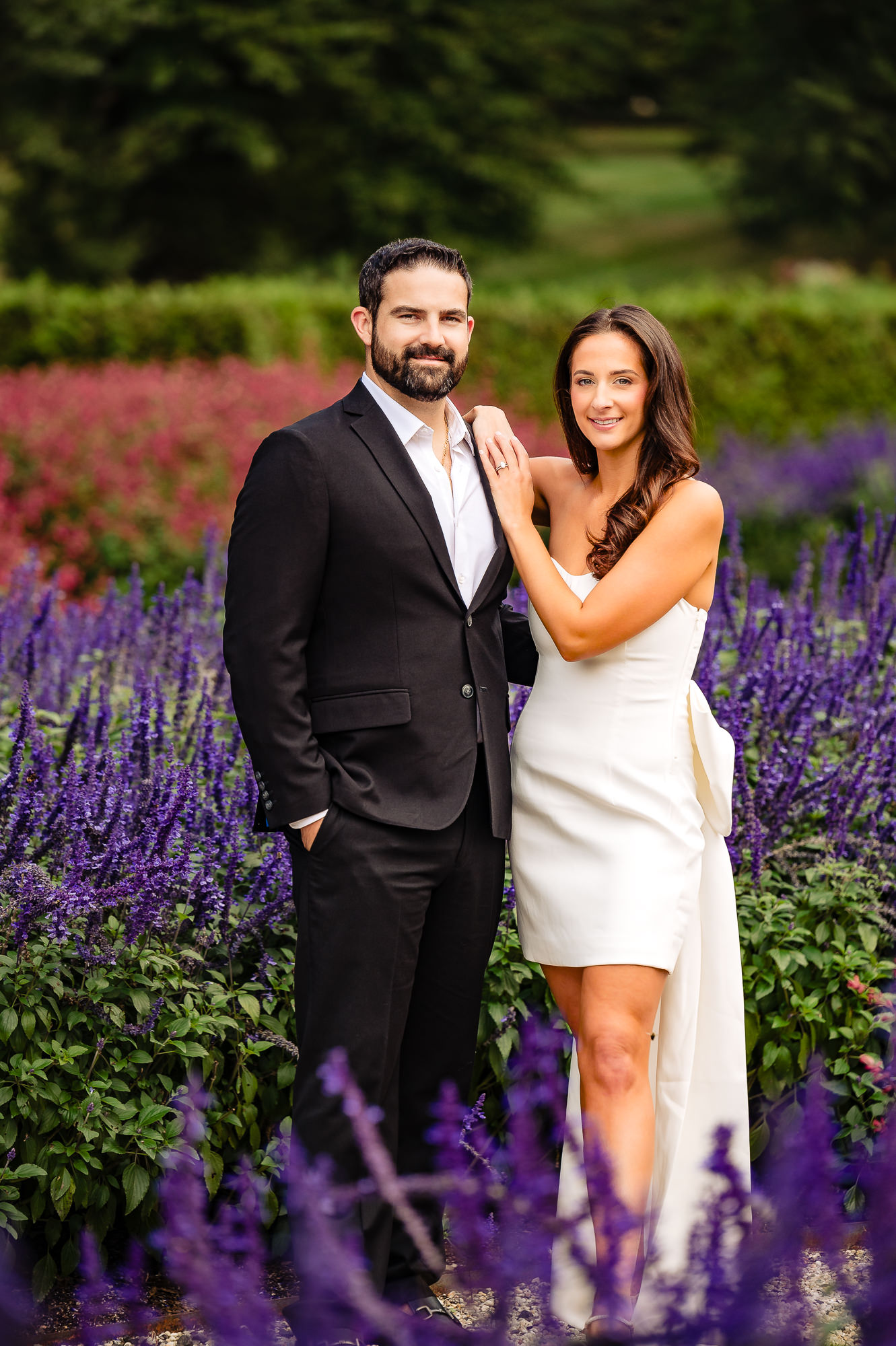 The couple shares a loving smile, gazing at each other during an engagement photoshoot in the gardens of Nemours Estate.