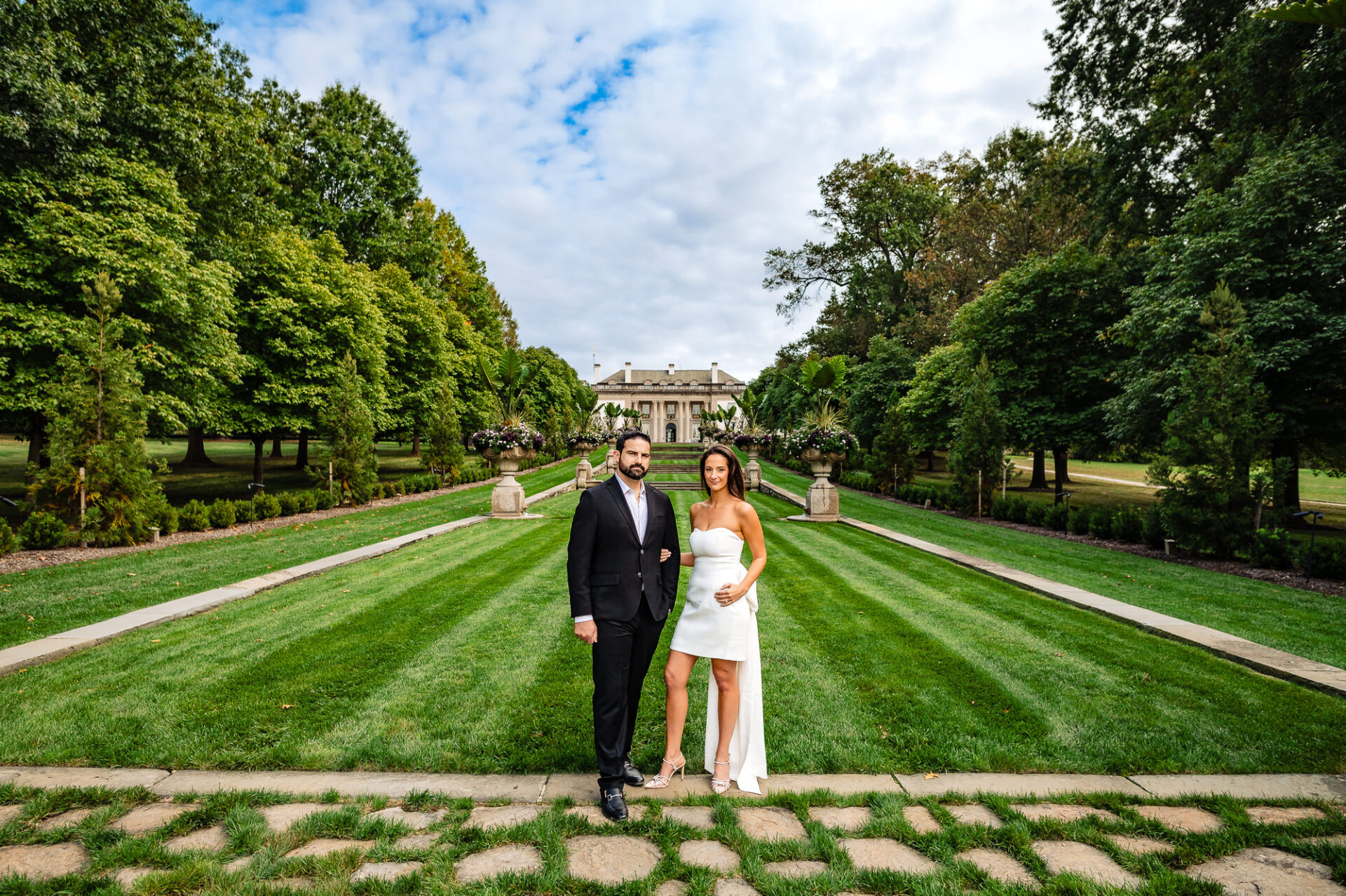 A couple smiles and looks into each other's eyes during an engagement photoshoot in the gardens of Nemours Estate.