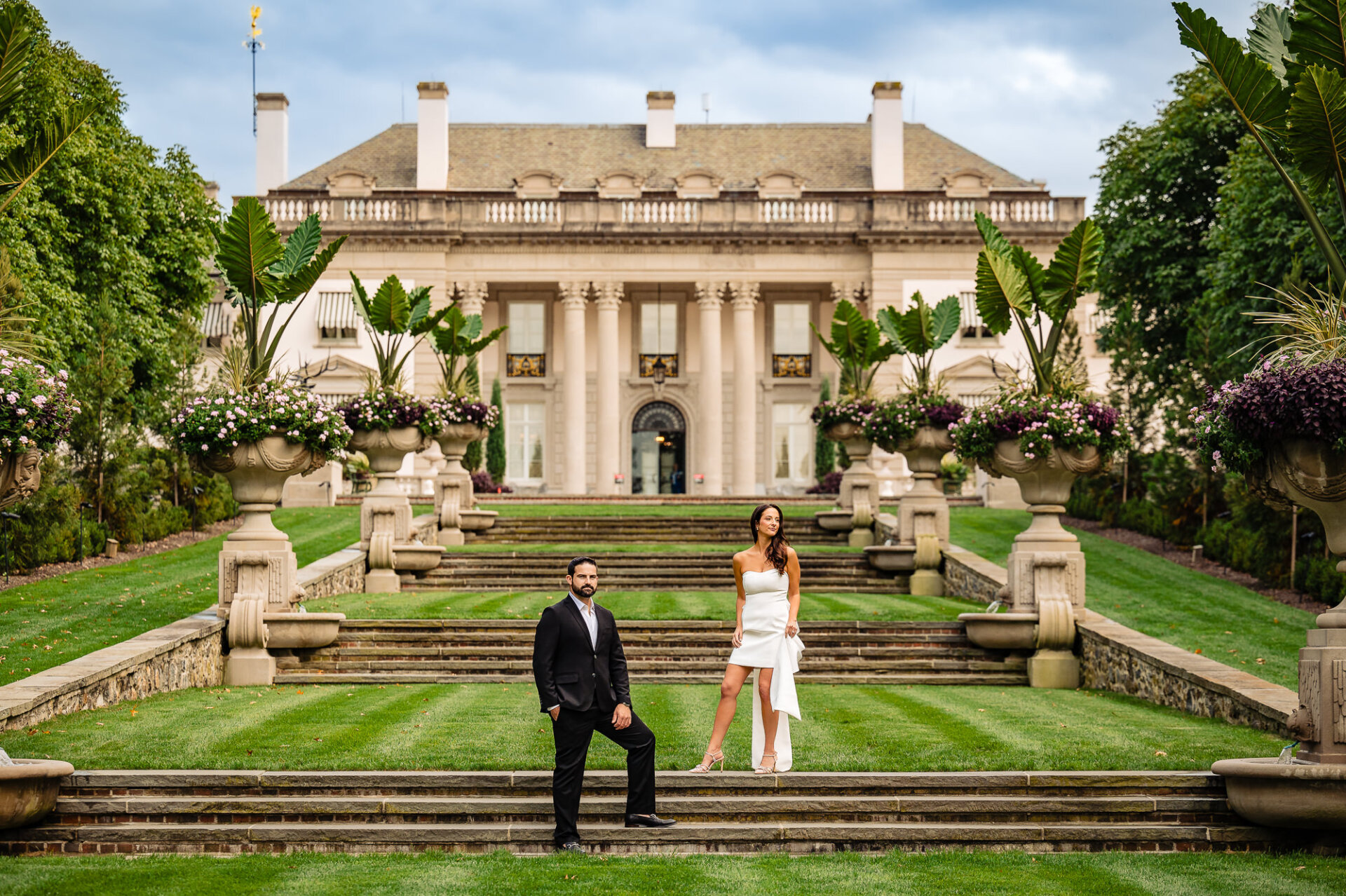 In the gardens of Nemours Estate, the couple shares a joyful moment, smiling at each other during their engagement session.