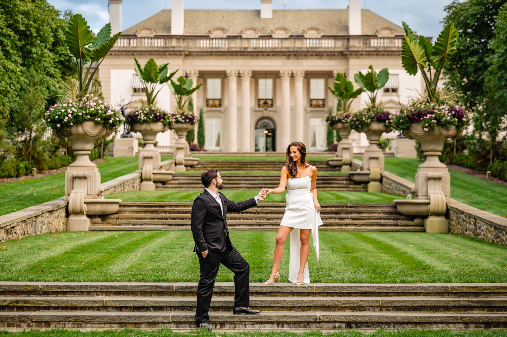 Smiling at one another, the couple stands in the garden of Nemours Estate during their engagement photoshoot.
