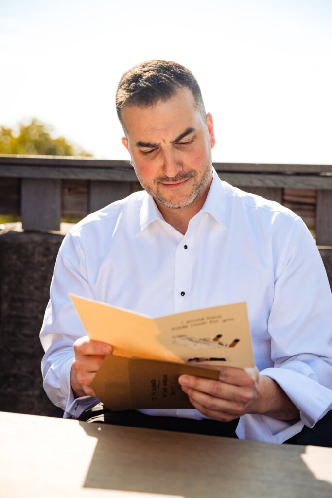 Groom sitting and reading a heartfelt card from the bride on their wedding day.