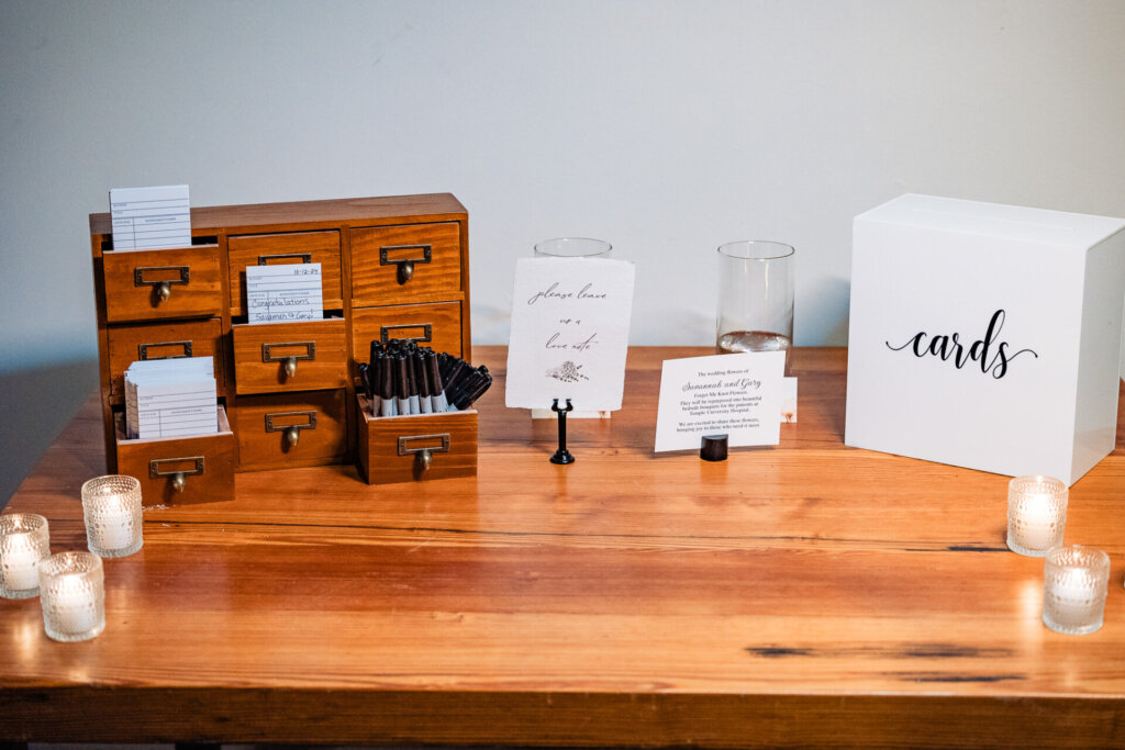 Wooden wedding decor with cards for guests to fill out and a calligraphy sign that reads 'Cards'