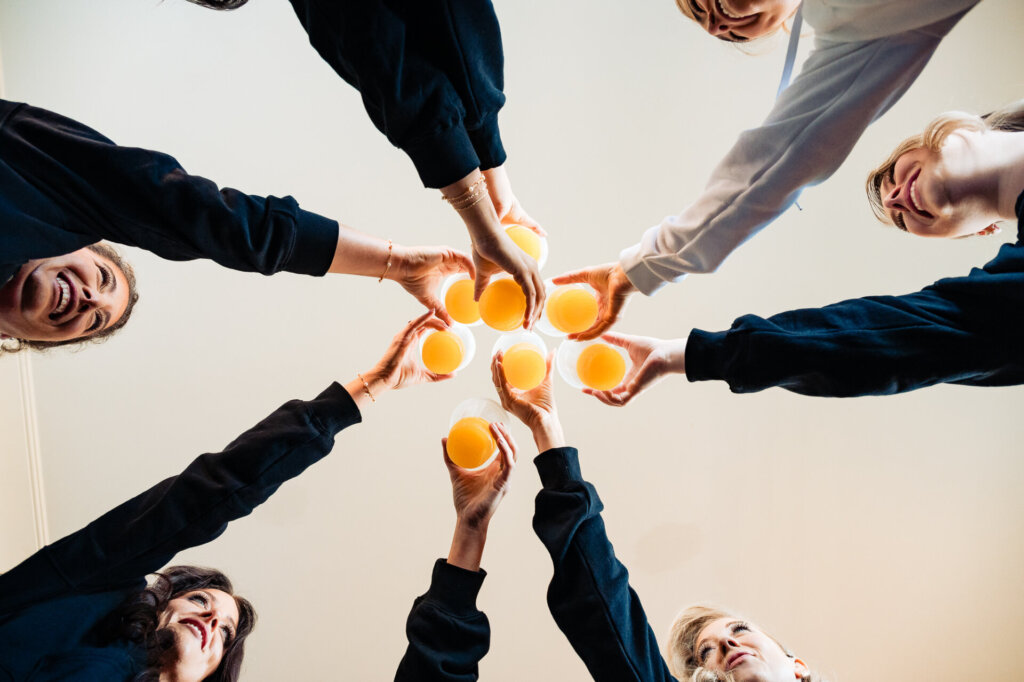Low-angle shot of the bride and bridesmaids raising their glasses in a celebratory toast.