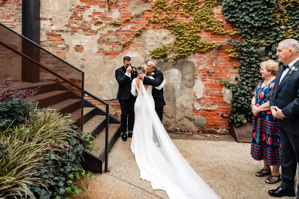 Bride's father embracing her warmly before giving her to the groom during the wedding ceremony