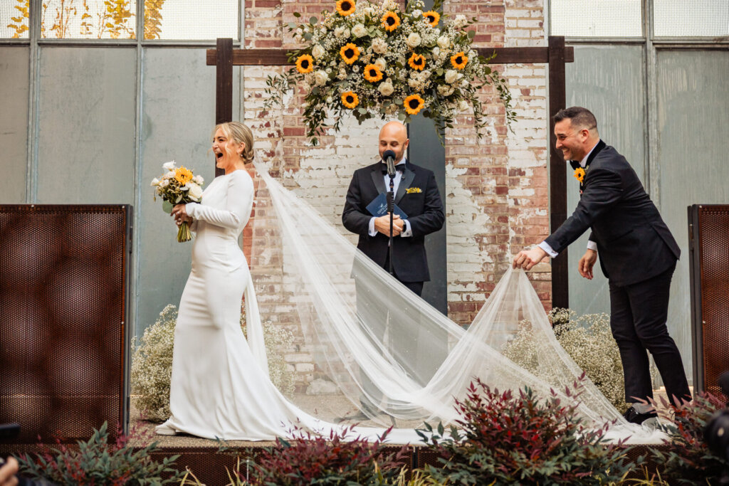 Groom gently adjusting the bride's veil on the altar during their wedding ceremony
