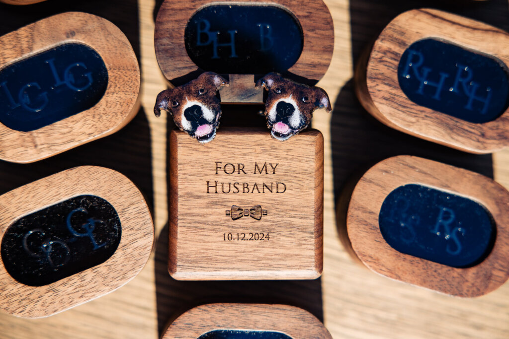Wooden keepsake box engraved with 'For My Husband 10-12-2024,' surrounded by personalized wooden cufflink boxes, with two dog-shaped cufflinks on top.