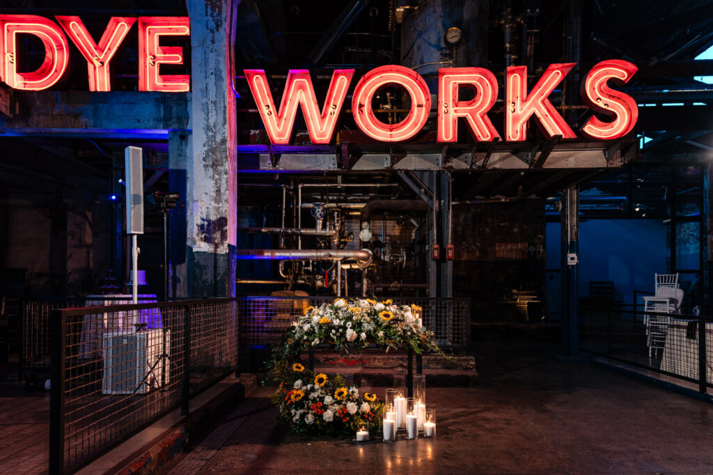 Shot of the decorative floral arrangement with candles at the venue, set against a backdrop of the 'GLOBE DYE WORKS' sign