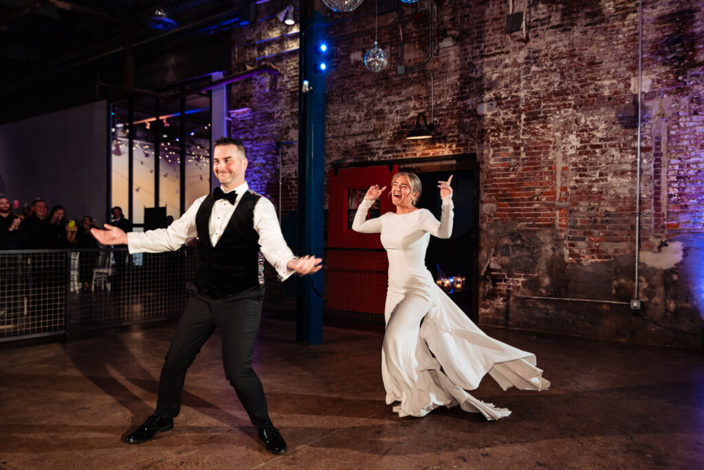 Bride and groom spinning on the dance floor during their first dance, surrounded by warm lighting and guests.
