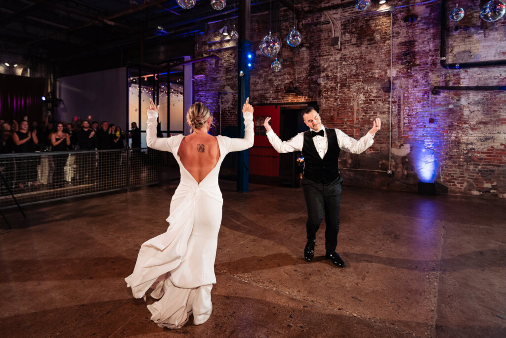 Bride twirling gracefully on the dance floor while the groom looks on lovingly, both enjoying the celebration