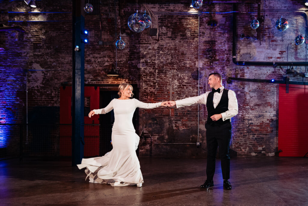 Bride and groom dancing together on the floor, with the groom leading and the bride spinning in her gown