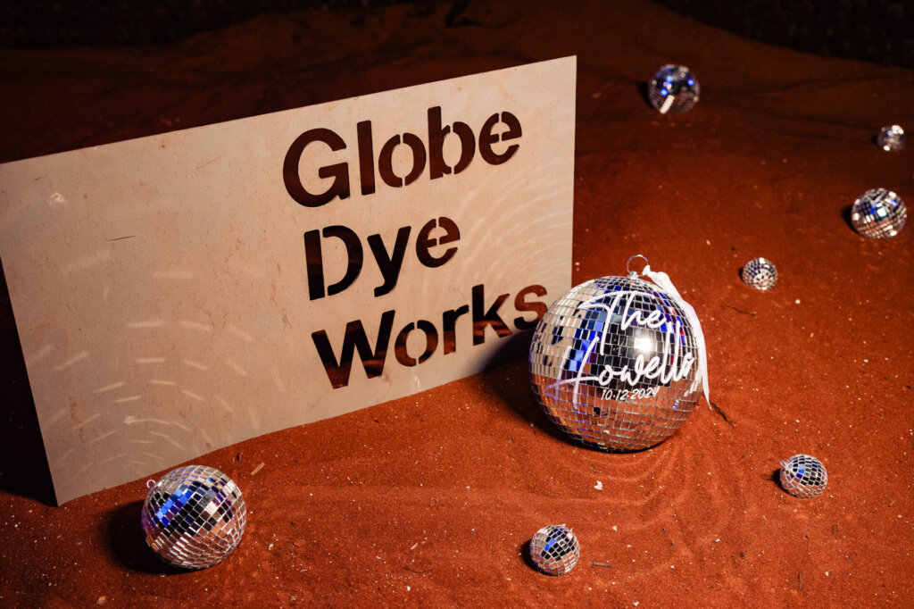 Wedding sign reading 'Globe Dye Works' with decorative disco balls placed on the ground.