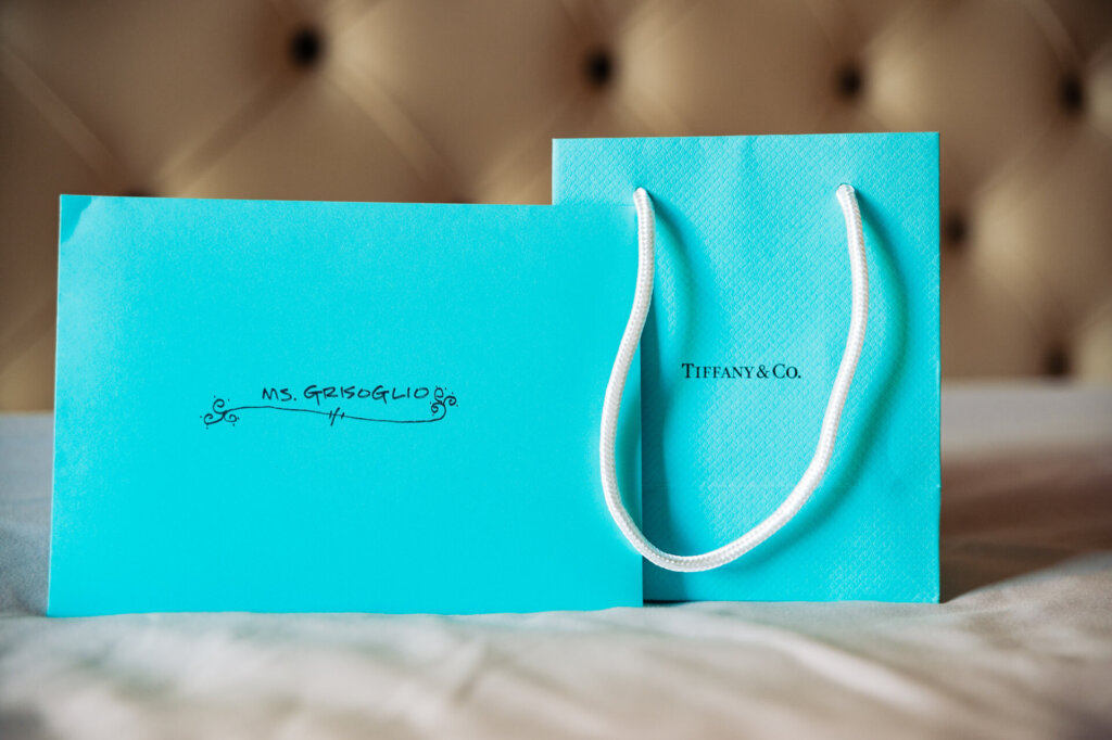 Mint green Tiffany & Co. paper bags customized with the groom's last name and 'Mrs.' written before it, designed for the bride.