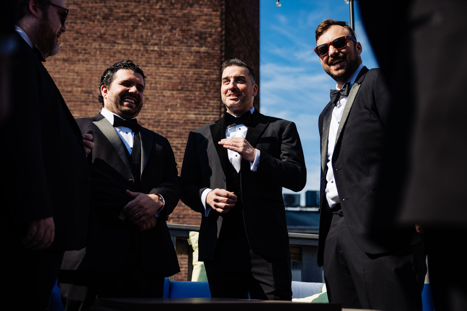 Groom and groomsmen standing together, engaged in conversation and sharing a light moment.