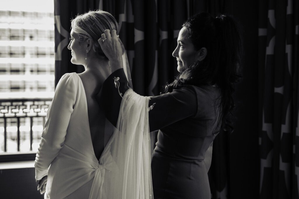 Black and white photograph of the bride and her mother adjusting the bride's hair before the ceremony