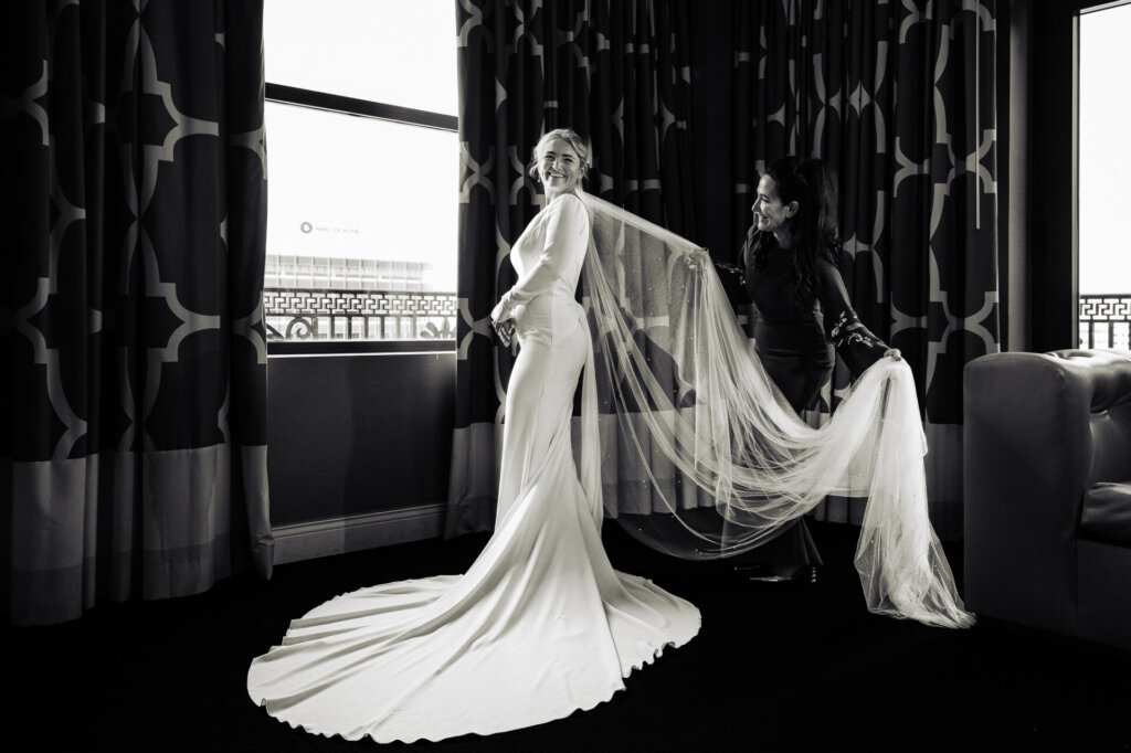 Black and white photograph of the bride's mother adjusting the bride's veil with care.