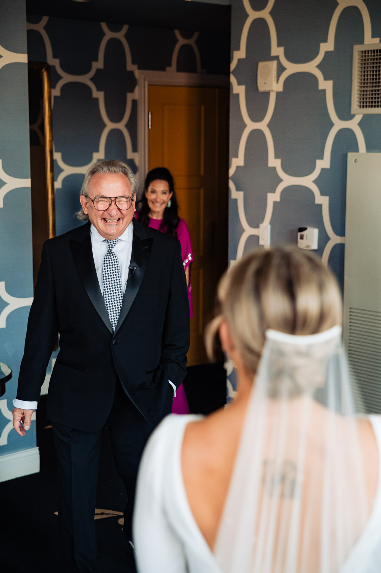 Bride's father smiling warmly during his first look at her in her wedding gown.