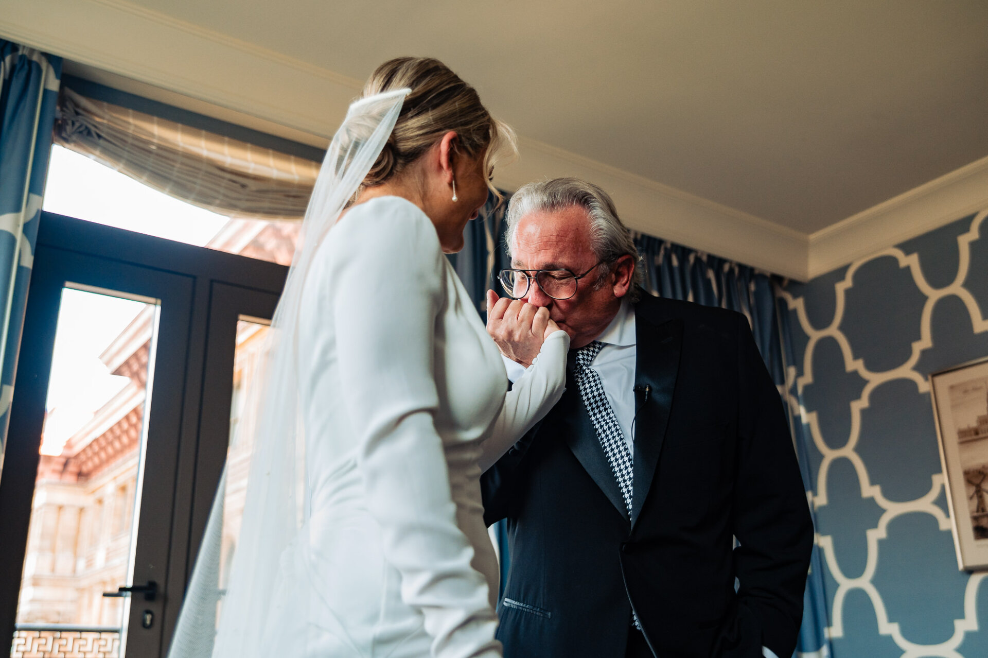 Bride's father kissing the back of her hand with emotion during his first look at her in her wedding gown