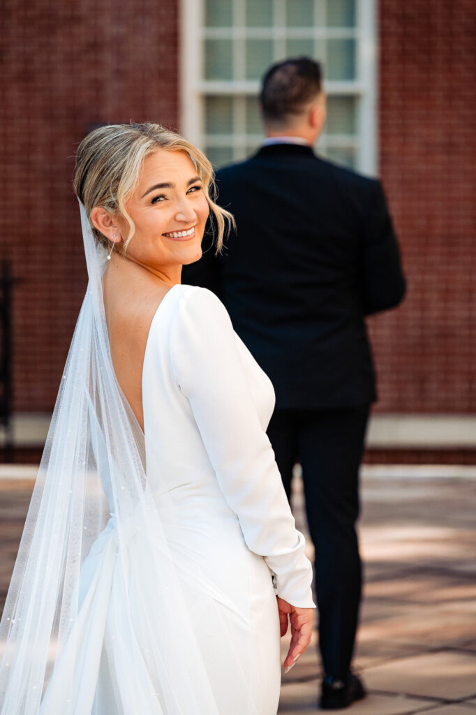 Bride looking back at the camera, smiling warmly during the couple's first look