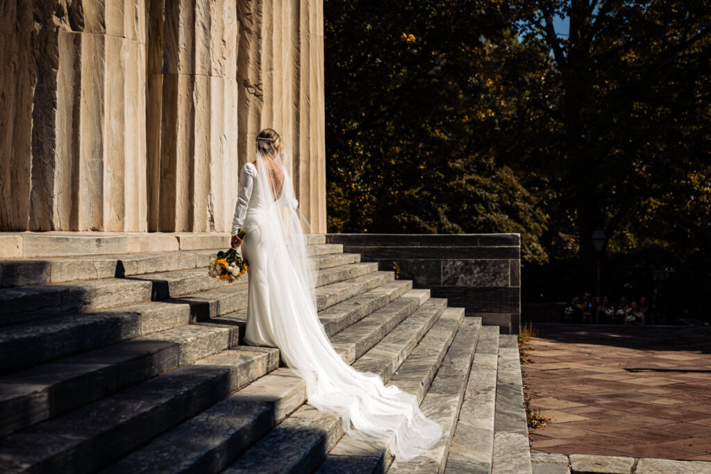 Bride walking up the staircase, her wedding gown flowing and trailing behind her