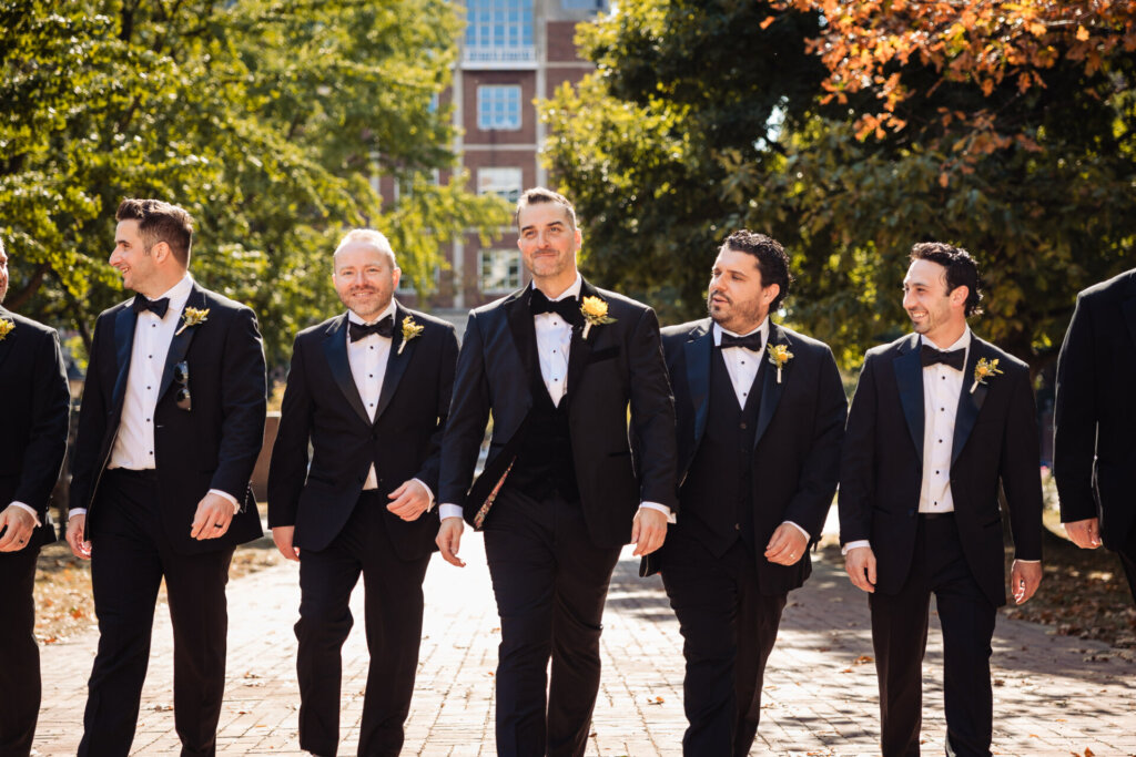 Groom posing confidently while walking with his groomsmen on the wedding day.