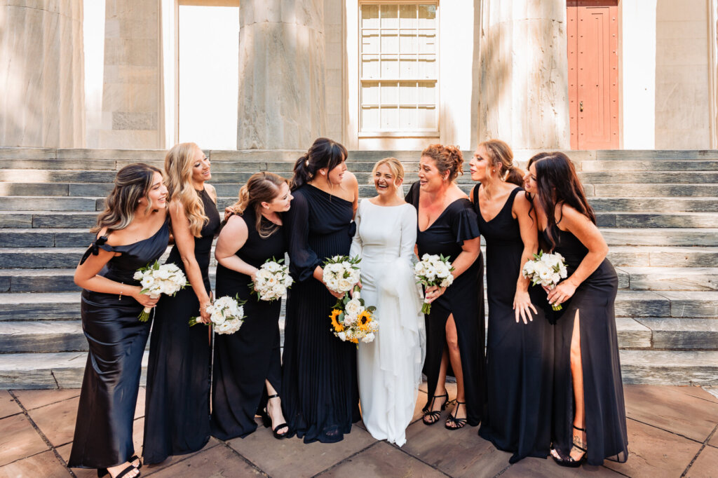 The bride and bridesmaids posing for a photo, each holding their bouquets and smiling brightly