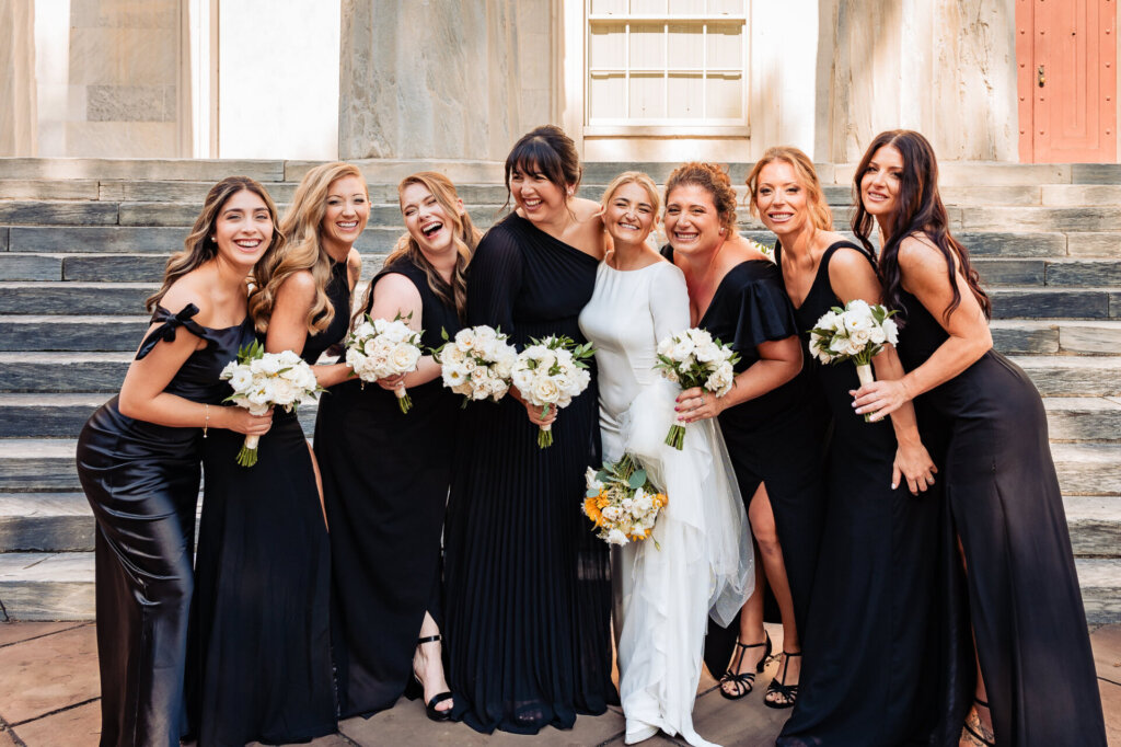 Bride and her bridesmaids standing together, smiling while holding their beautiful bouquets.