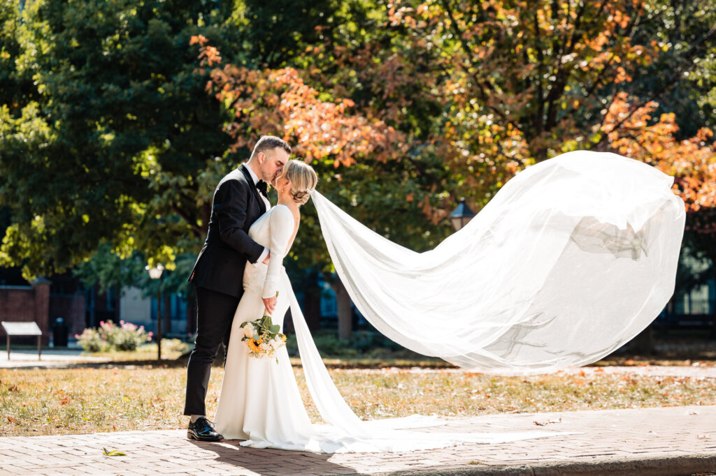 Bride and groom sharing a tender kiss in a peaceful natural setting, surrounded by greenery.