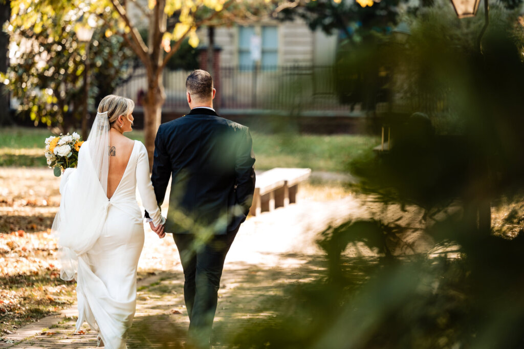 Bride and groom standing with their backs to the camera, holding hands in a scenic outdoor setting