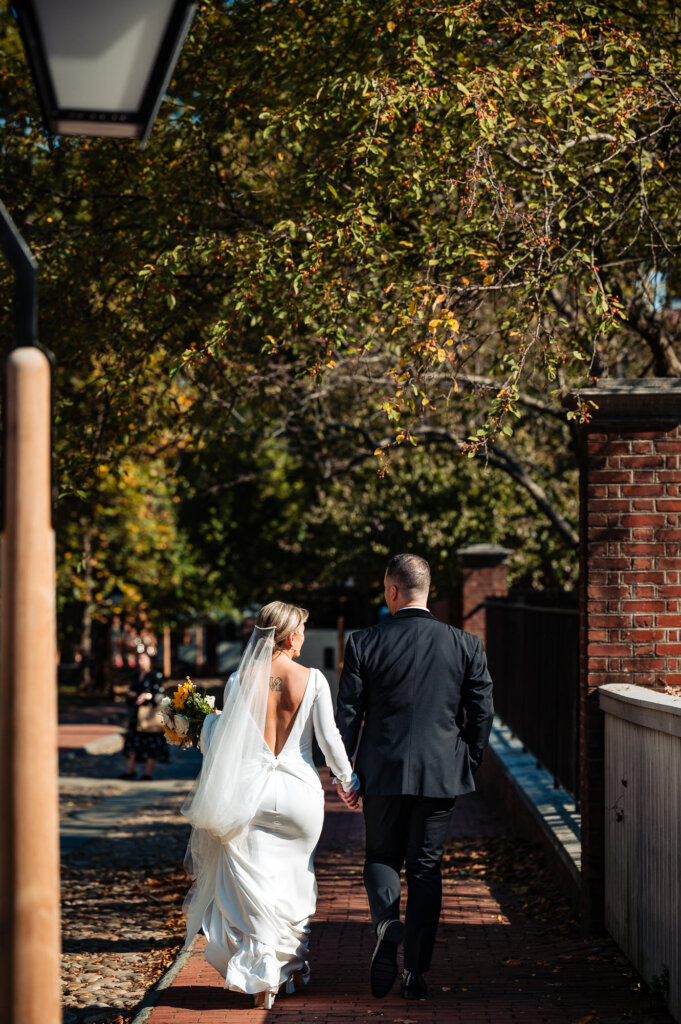 Back shot of the bride and groom looking at each other lovingly as they walk together through a beautiful natural setting.