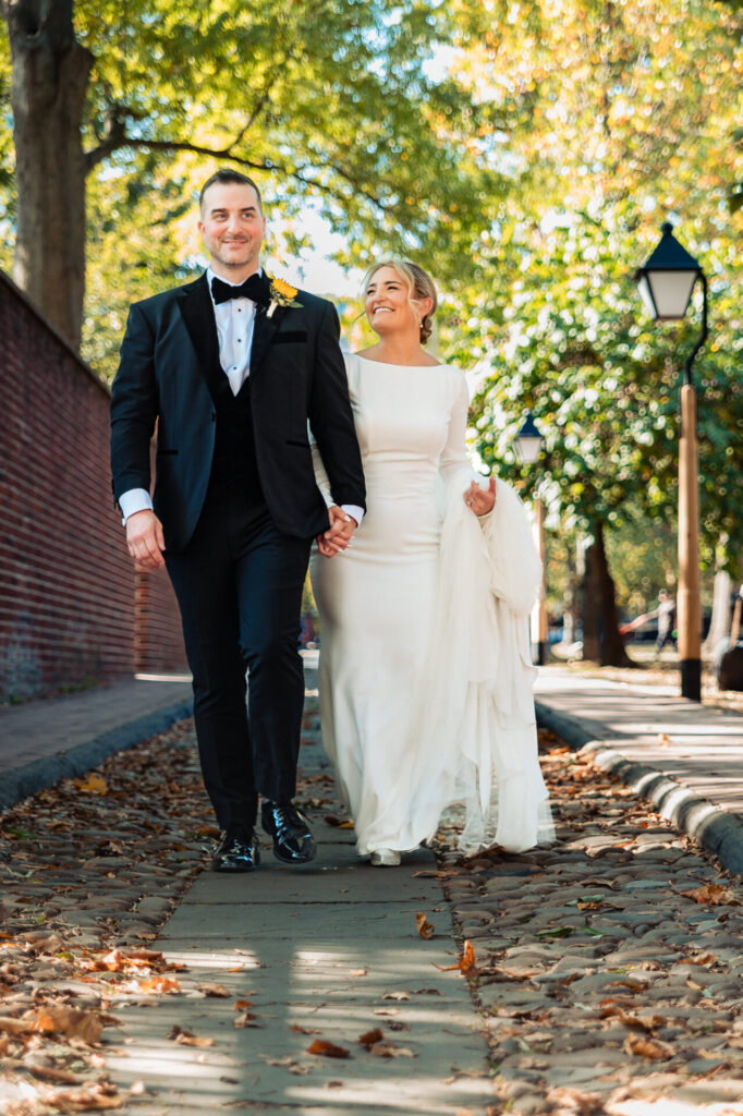 Bride and groom holding hands, walking together with smiles on their faces.