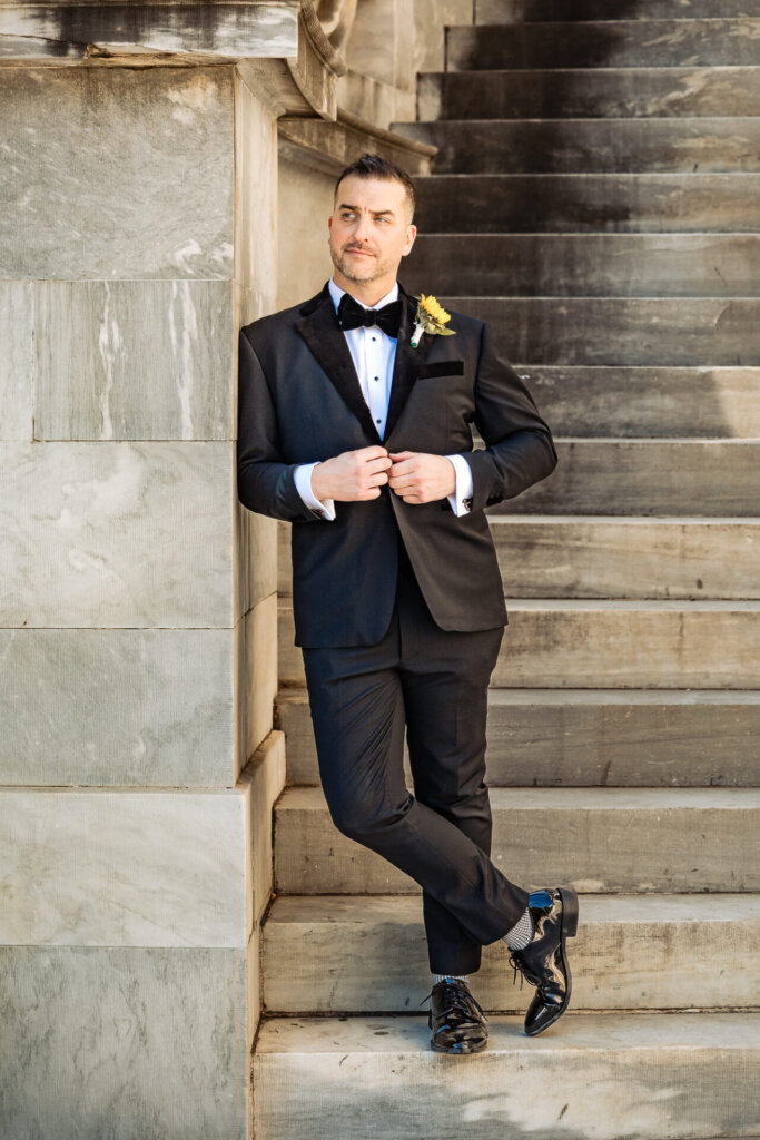 Bridal portrait of the groom confidently posing on the stairs, looking dapper in his wedding suit.