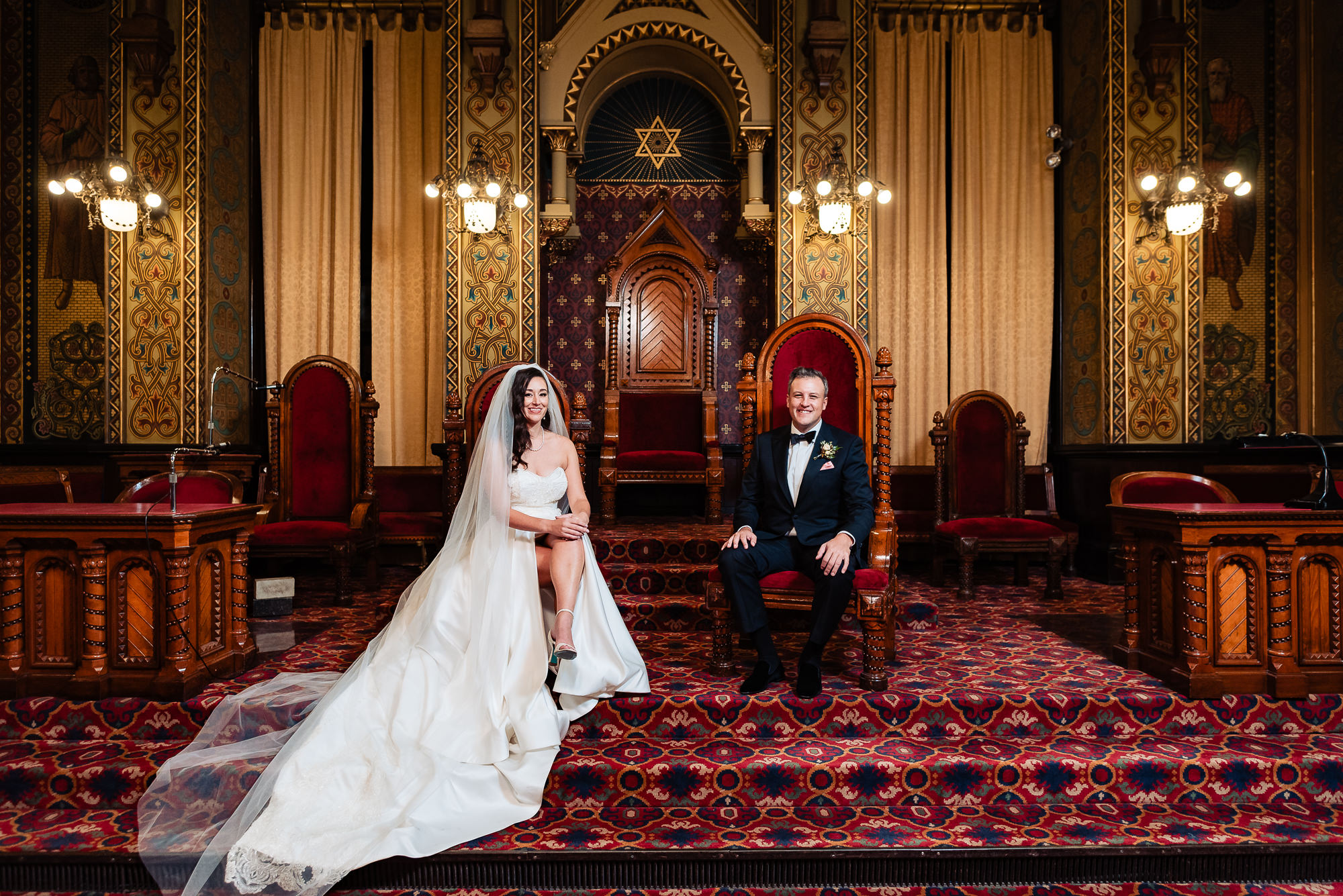 Bride and groom sitting side by side in royal-style chairs, smiling at their Beautiful Wedding at One North Broad