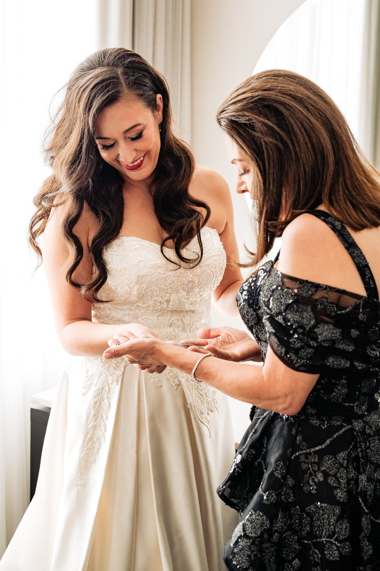 Bride sharing a moment with her mother while holding an accessory