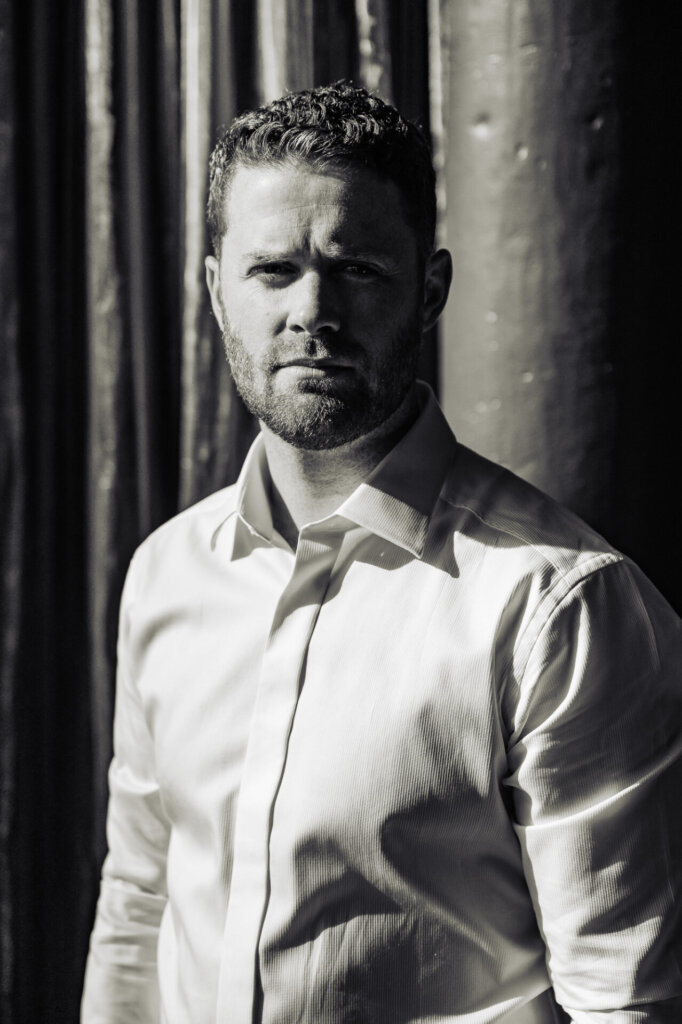 Black and white portrait of the groom, staring intently into the camera, conveying strength and focus.