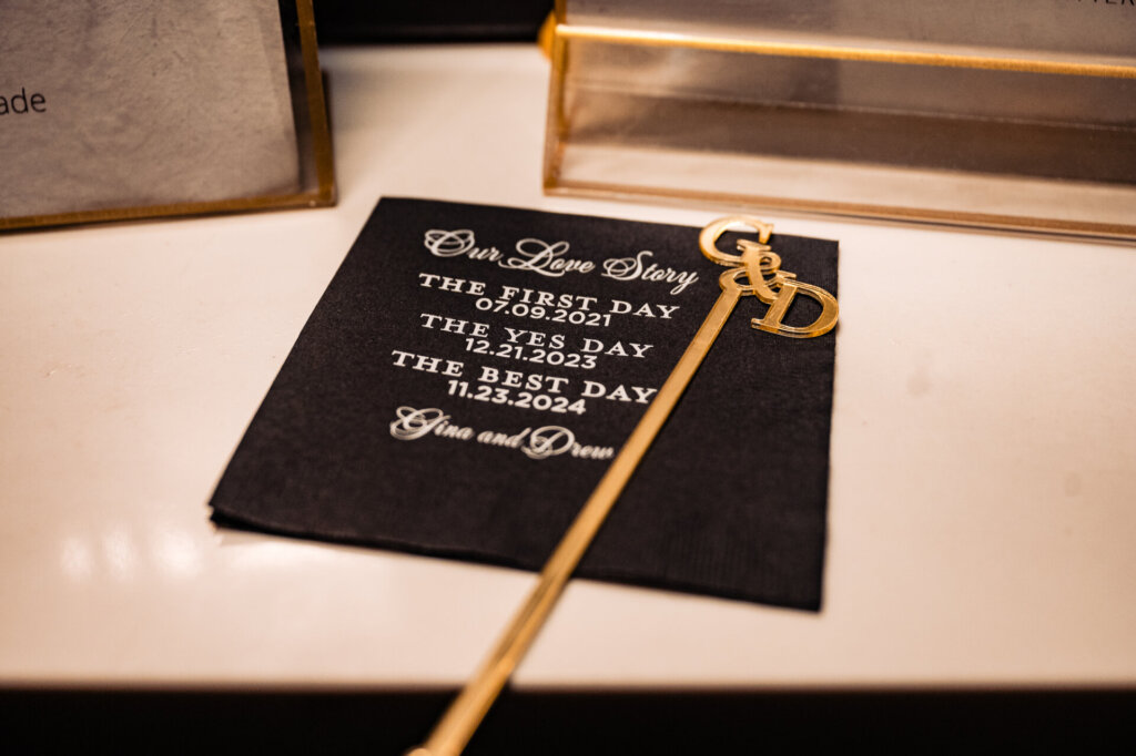 Close-up of a custom wedding sign reading 'Welcome to Gina and Drew's Wedding' with delicate gold accents