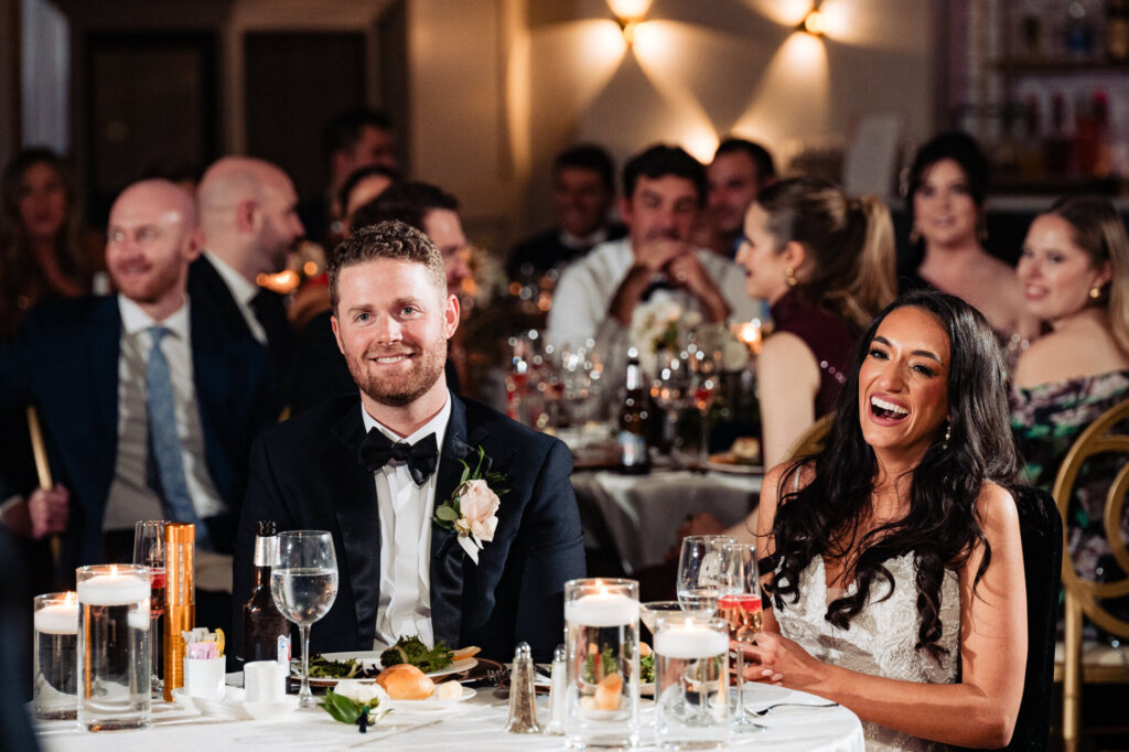 The bride and groom sharing a moment of joy during the reception, seated at their special table.