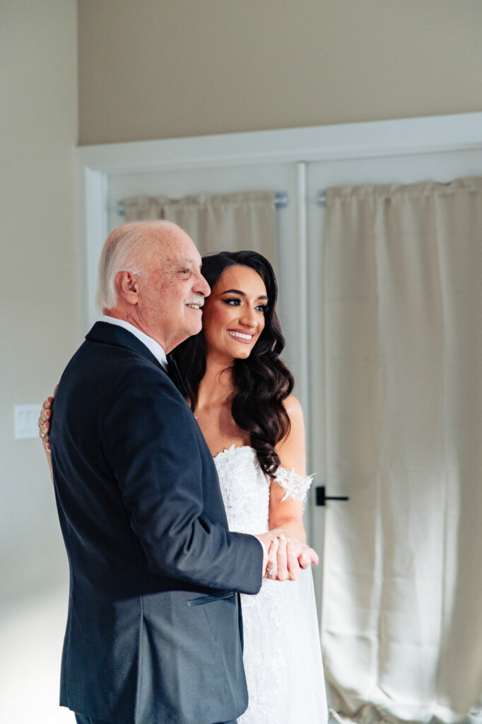 Father of the bride and his daughter standing together, sharing a conversation before the ceremony.