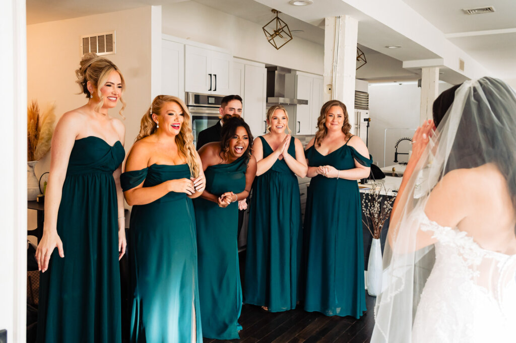 Bride and her bridal party standing together in the kitchen, celebrating and smiling as they prepare for the big day.