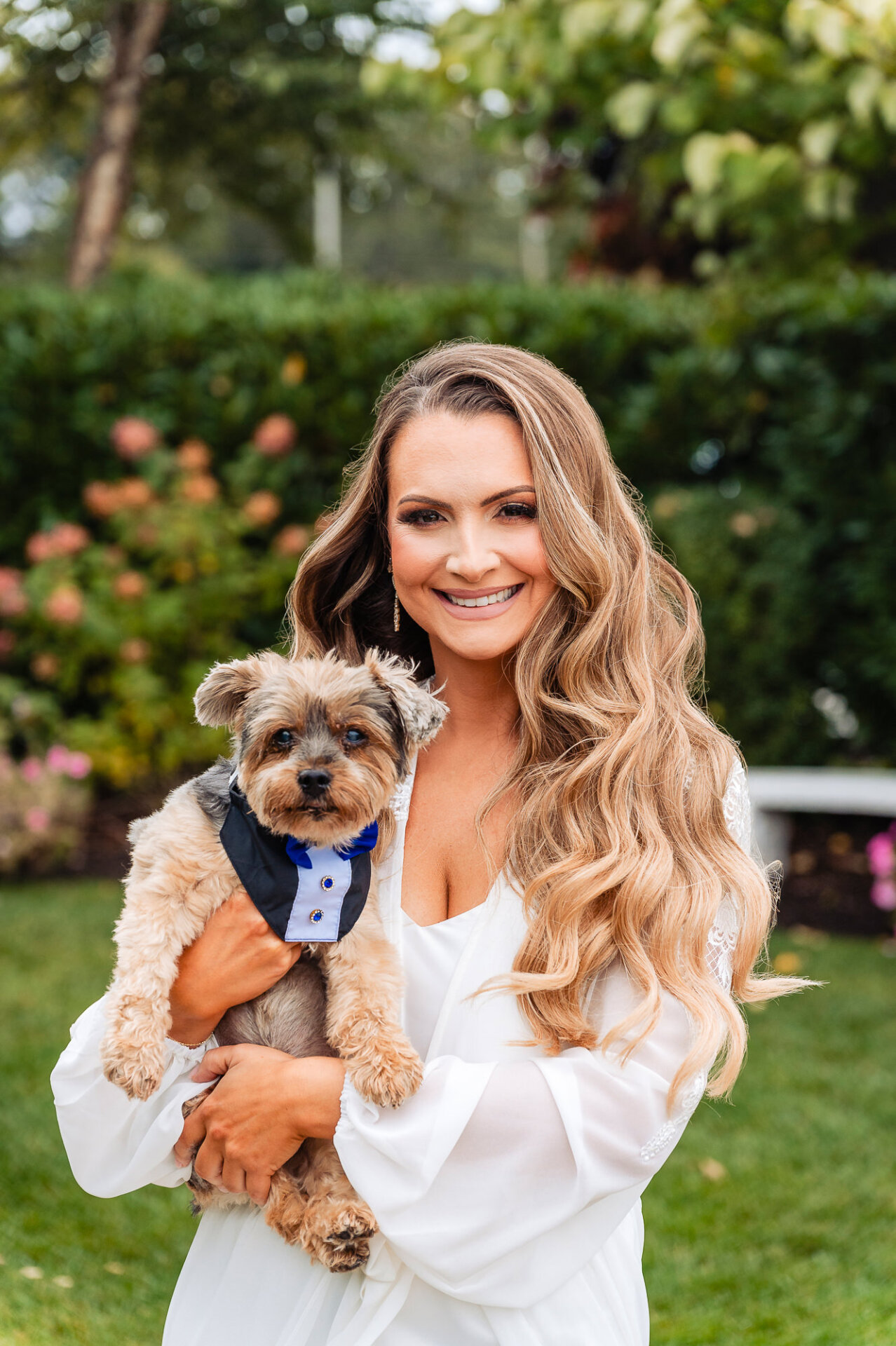 A heartwarming moment as the bride cuddles her pet, dressed up for the wedding.