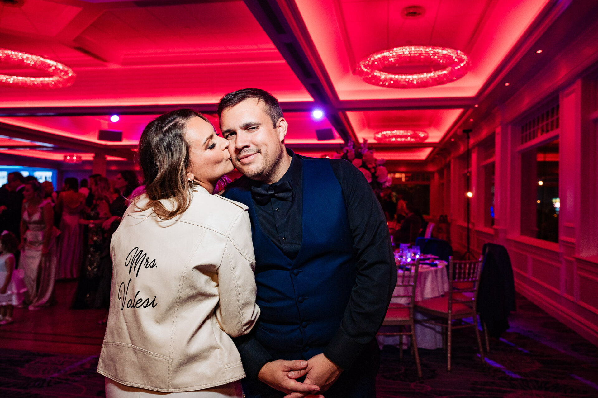 Couple posing in a dimly lit reception venue with red uplighting – A modern and stylish post-wedding moment.