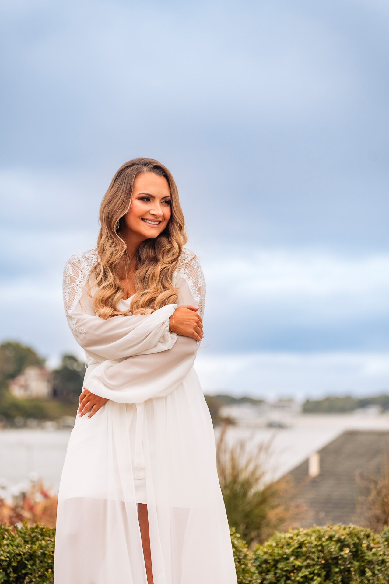 A serene bridal portrait with soft waves cascading over her shoulders against a scenic background.