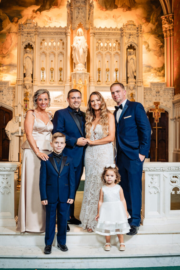 Bride, groom, and their young relatives posing inside the church – A beautiful generational portrait.