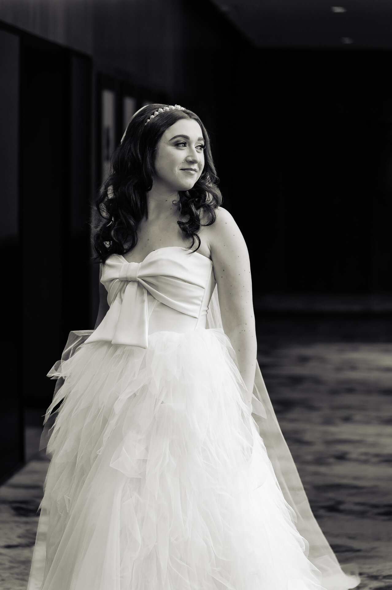 A candid moment of the bride smiling as she moves, her voluminous gown flowing with each step.