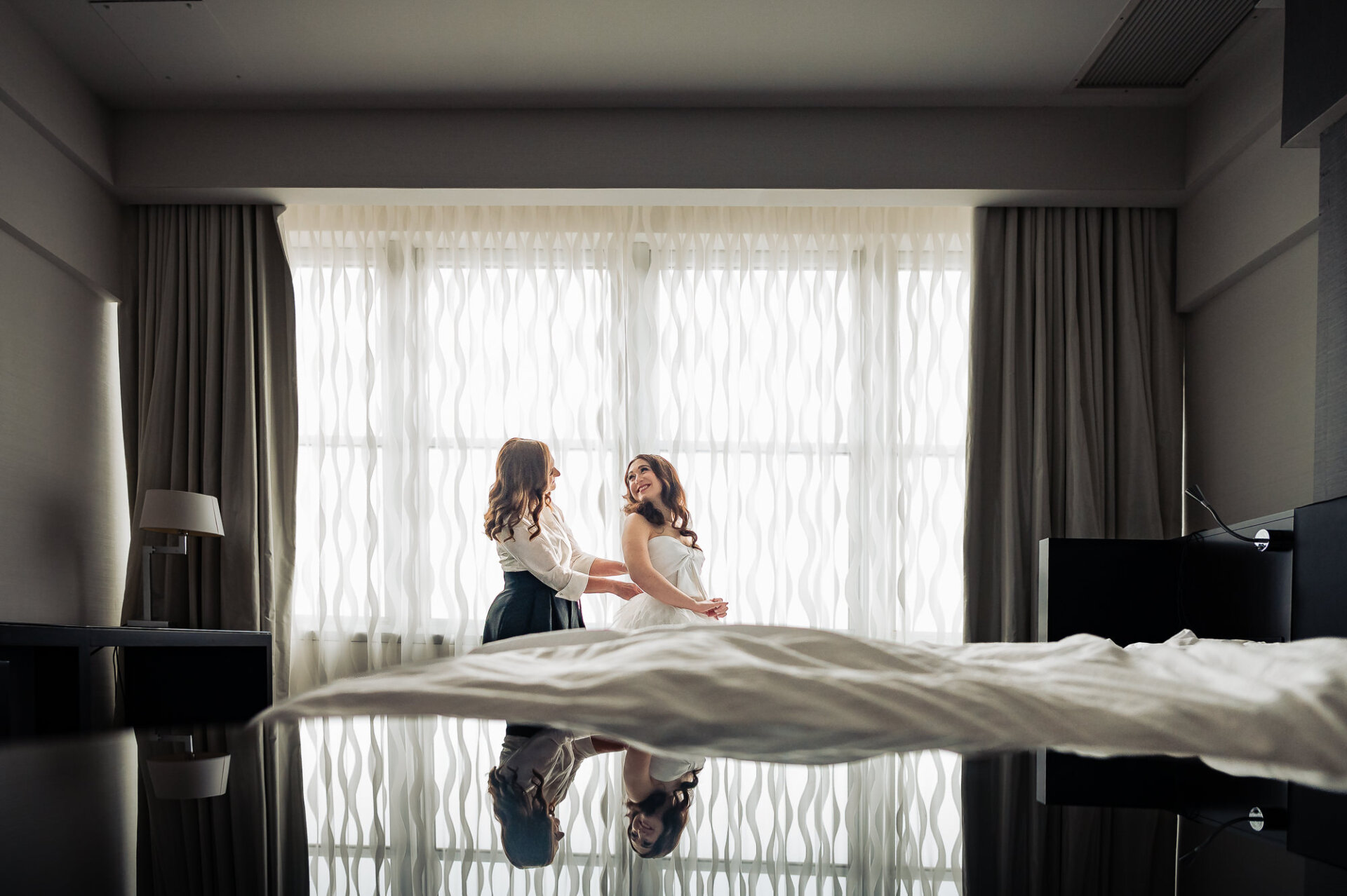 A dramatic shot of the bride and her bridesmaid standing together, with the wedding veil draped across the foreground.