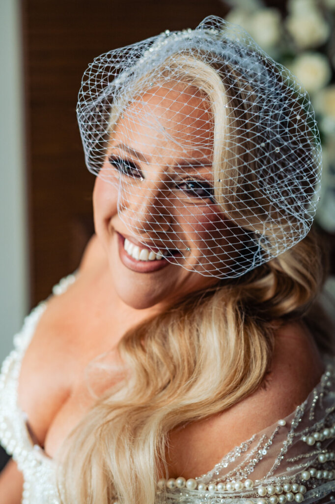 Bride smiling while wearing a birdcage veil