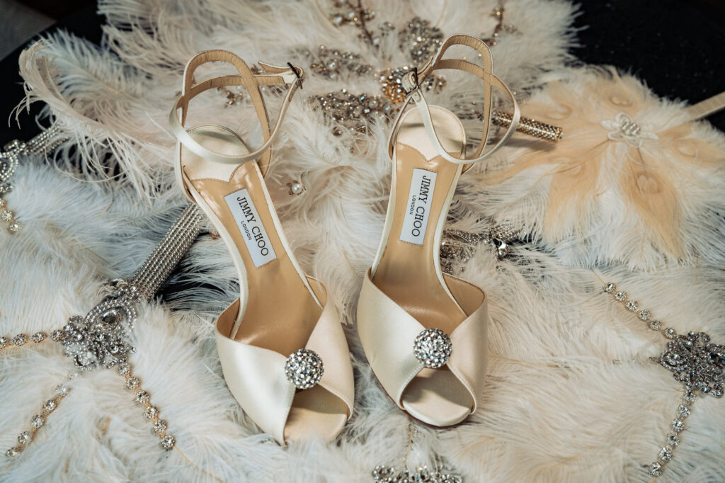 Pair of Jimmy Choo bridal shoes on a fur-like surface with jewelry
