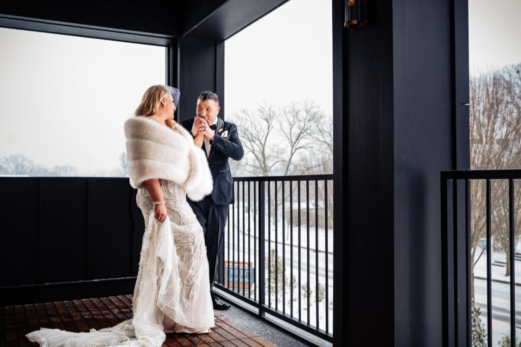 Bride and groom enjoying a moment together on a balcony in a winter setting